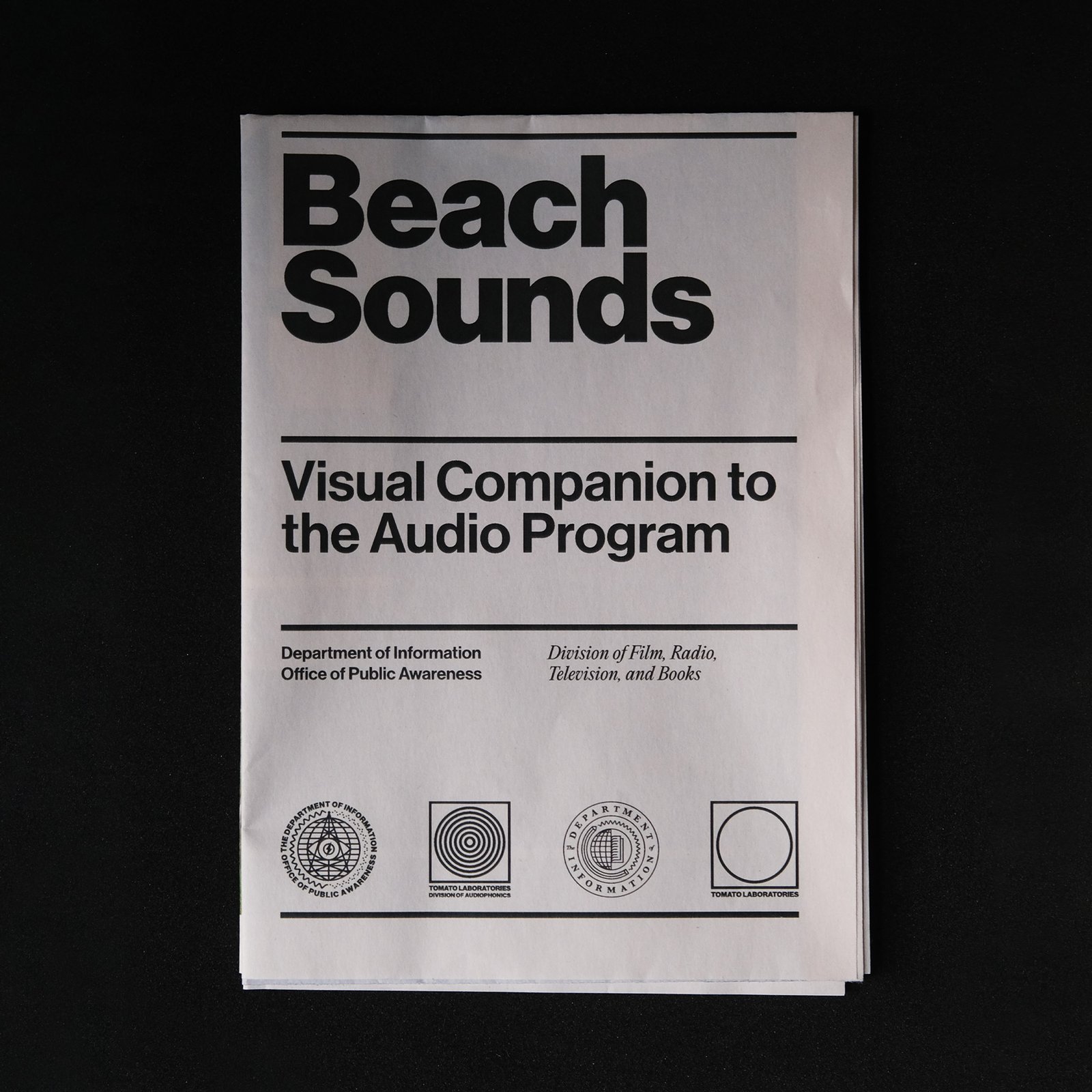 A folded newsprint that says Beach Sounds in black on white and Visual Companion to the Audio Program