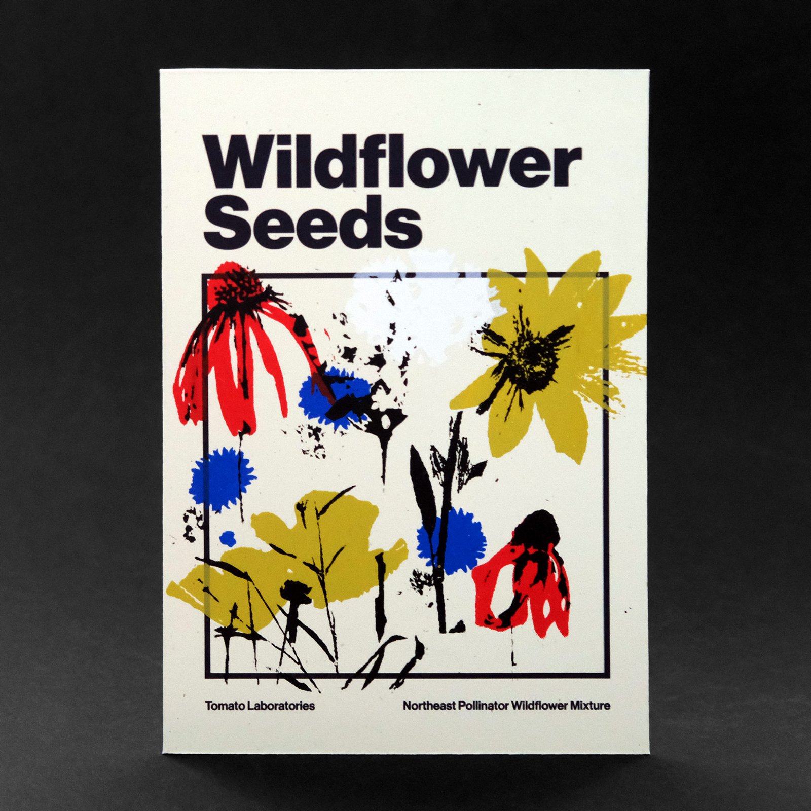 A colorful screen printed pack of wildflower seeds sits on top of a black background