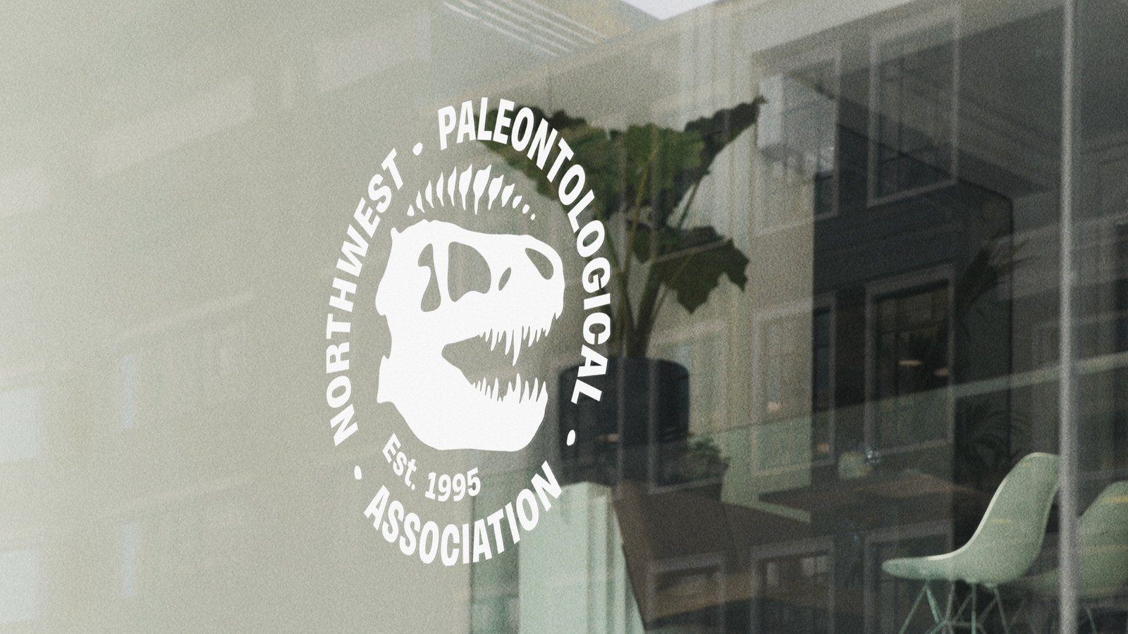 The Northwest Paleontological Association logo with a t-rex skull is seen on a glass window